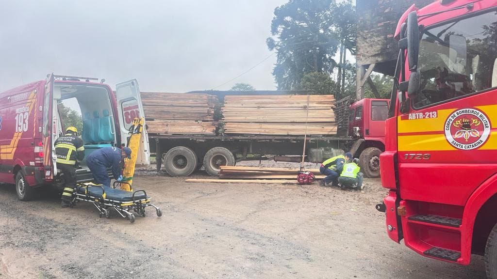 Caminhoneiro fica gravemente ferido após queda de carga de madeiras
