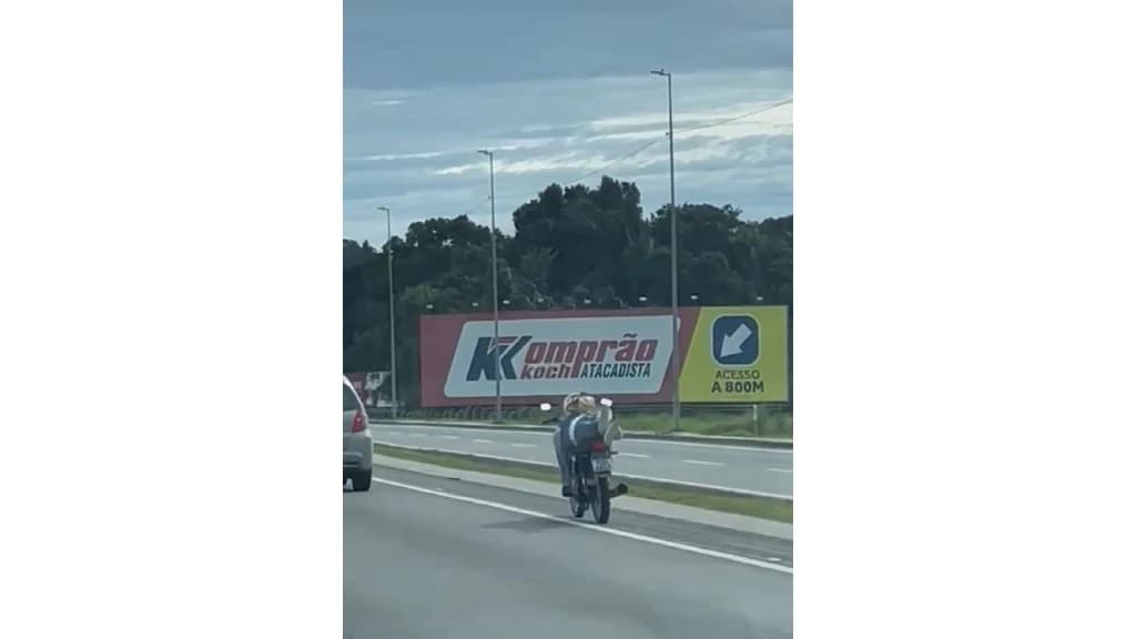 Jovem se arrisca ao conduzir motocicleta deitado na BR101 em Itapema
