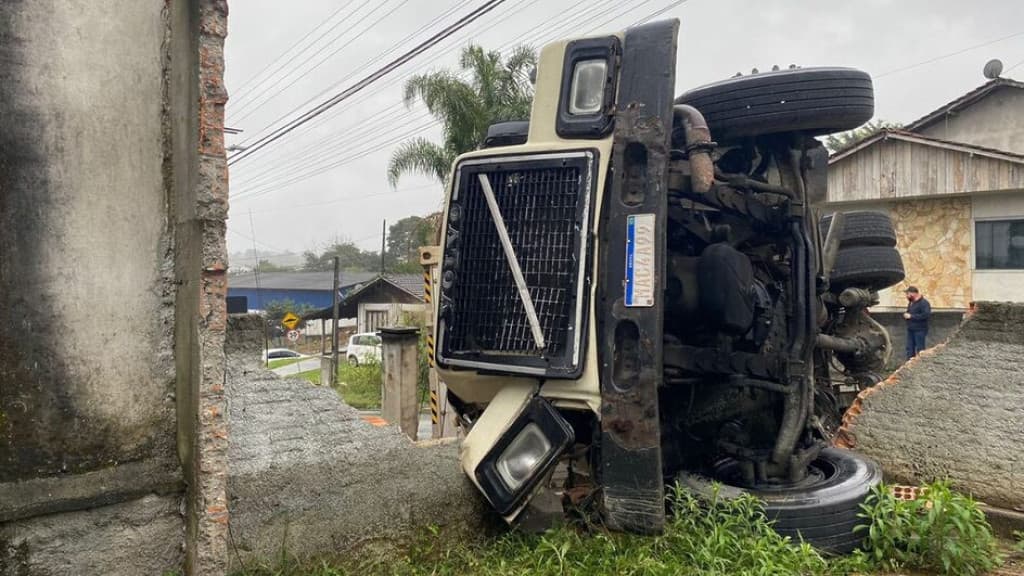 SUSTO: Caminhão tomba e destrói muro de residência