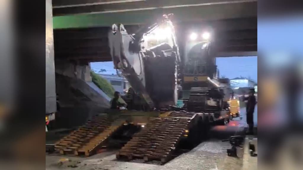 Caminhão carregado com escavadeira fica entalado sob viaduto na BR-101