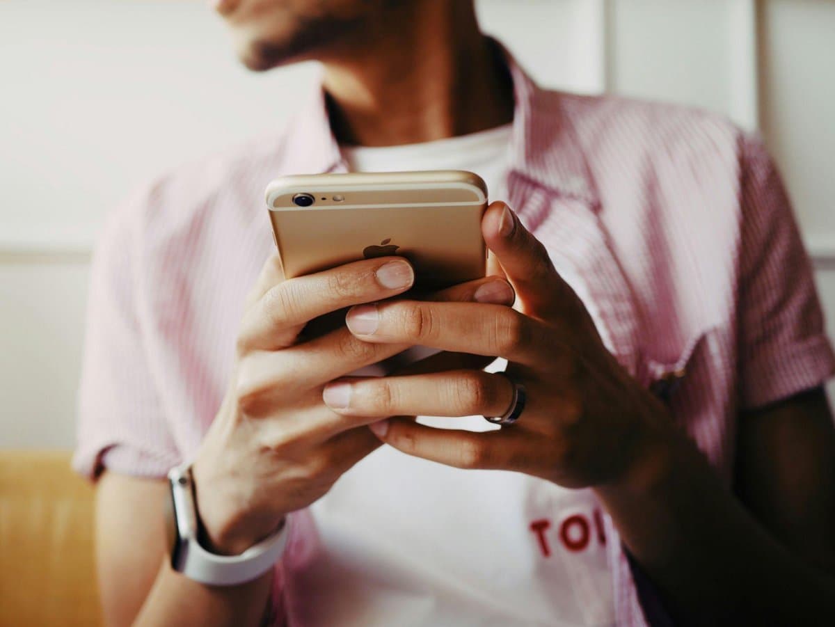 Homem segura celular com as duas maos enquanto usa um aplicativo