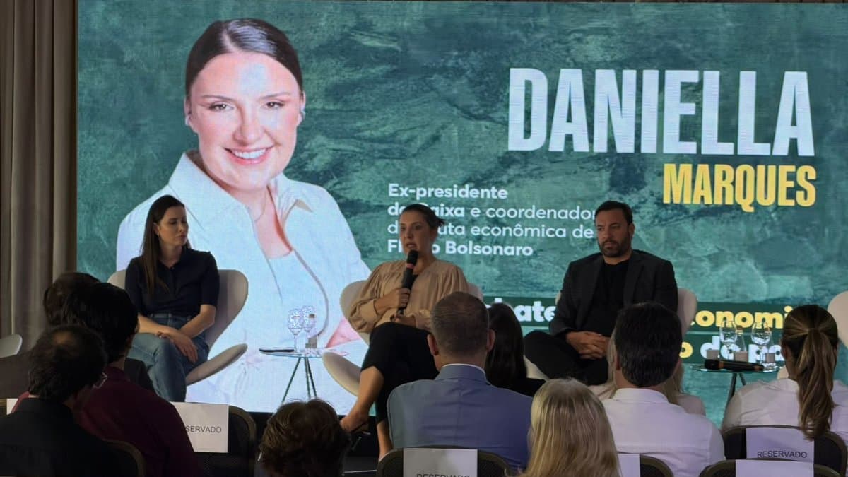 Economista Daniella Marques fala ao microfone durante painel com empresarios em Florianopolis, com seu nome projetado no telao