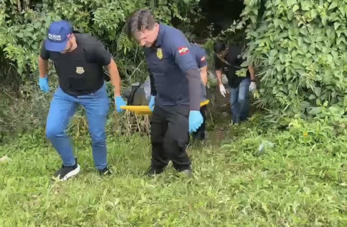 Agentes da Polícia Científica retiram o corpo de José Dário Siqueira Junior da área de mata na marginal da BR-101, em Itapema