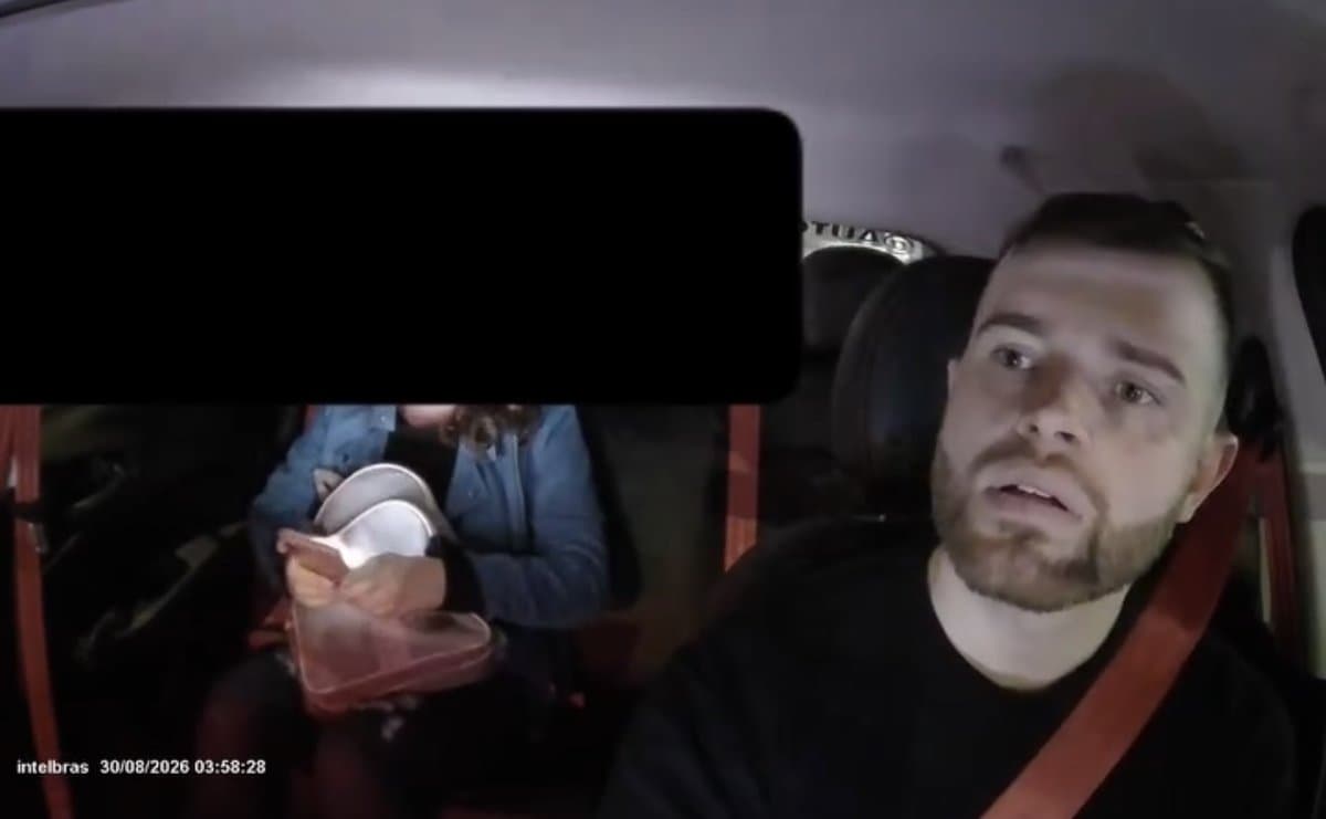Motorista de aplicativo ao volante durante a madrugada, com passageira no banco traseiro e rosto preservado