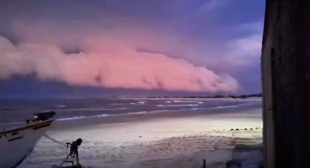 Nuvem de temporal se aproxima da praia com barco de pesca na areia, no Farol de Santa Marta, em Laguna