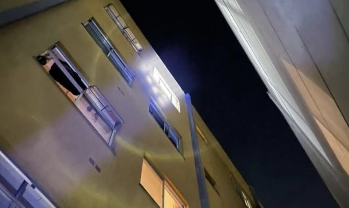 Fachada de prédio no Centro de Chapecó vista de baixo, à noite, com janela aberta no quarto andar