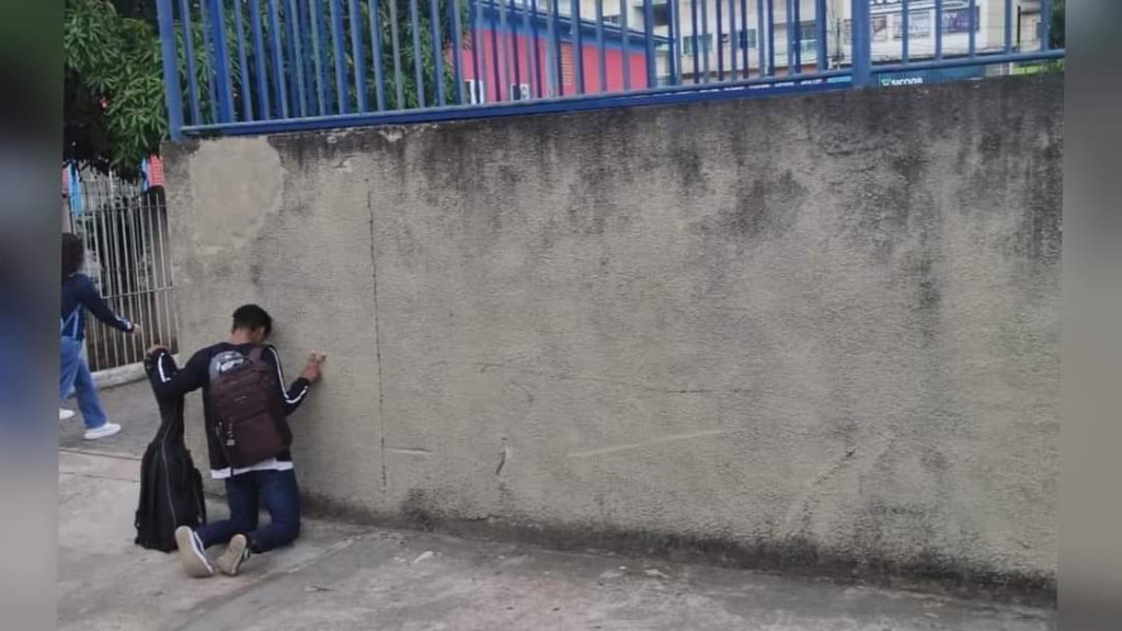 Adolescente faz oração em frente à escola antes de entrar em sala de aula