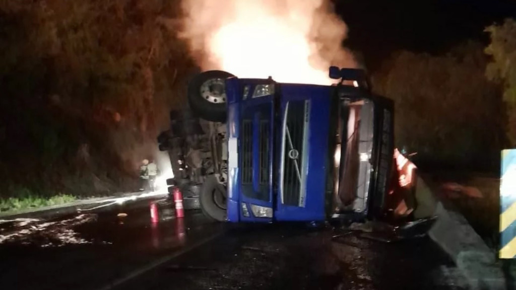 Carreta tomba e carga de madeira pega fogo na BR-116