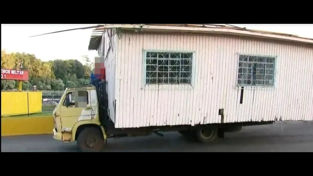 Caminhão é flagrado transportando casa com homem no teto do veículo