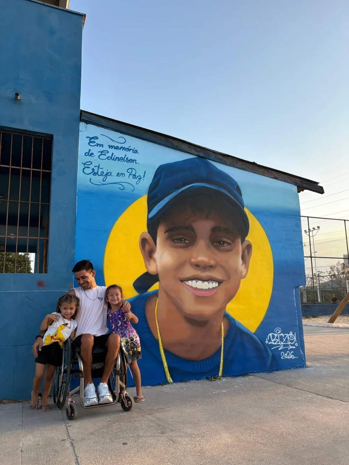 Pai ao lado do mural grafitado em homenagem a Edinelson em Palhoça