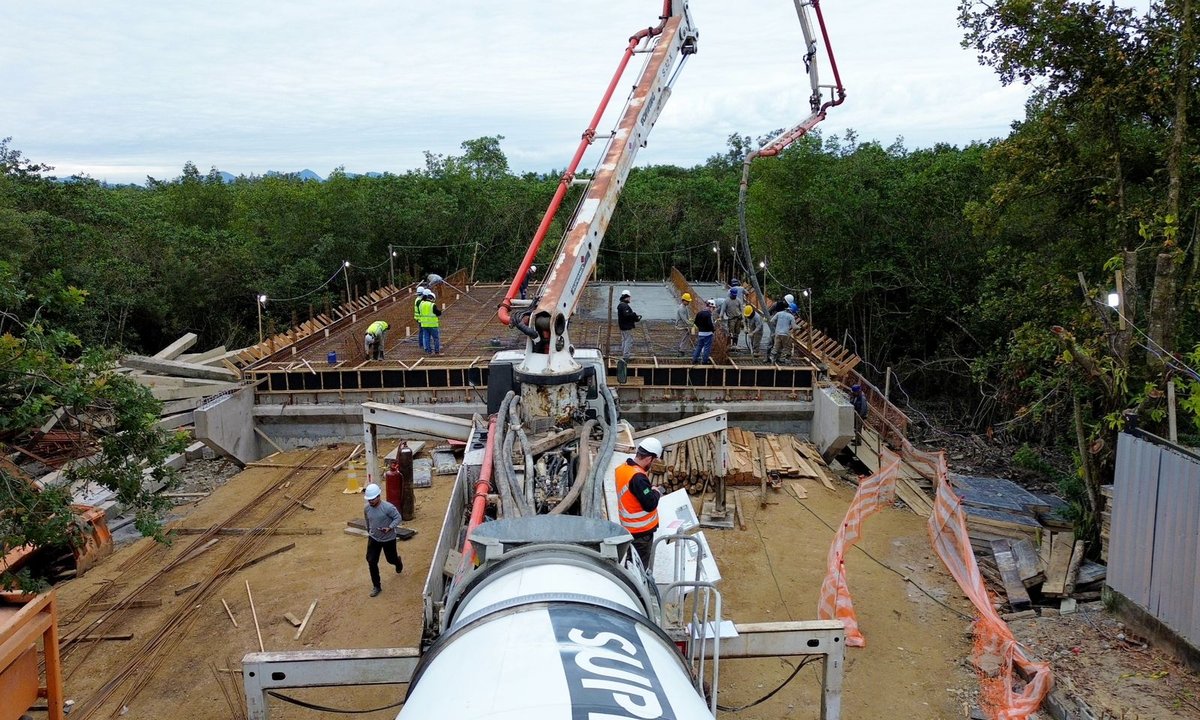 Equipes despejam o concreto sobre a armação durante a concretagem