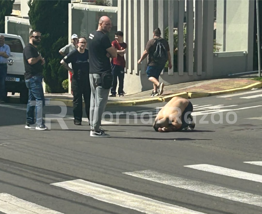 Pessoas observam homem caído sobre a faixa de pedestres na Rua Lauro Muller, no centro de Lages