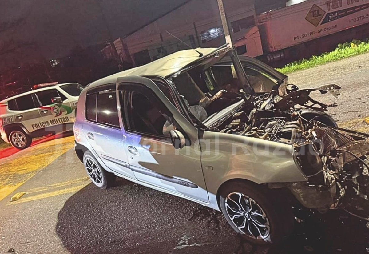 Frente do Renault Clio destruída na BR-280, com viatura da Polícia Militar ao fundo