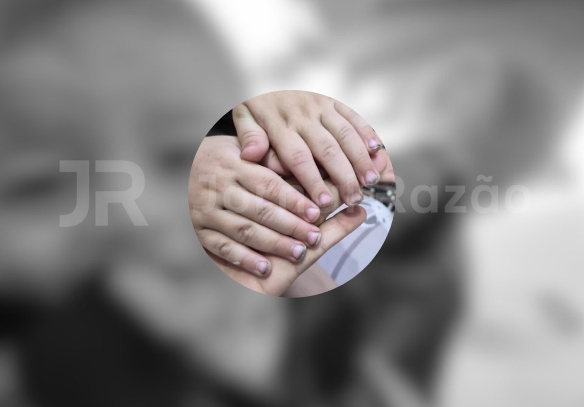 Mãos do menino de quatro anos que sobreviveu, com unhas sujas, sobre a palma de um adulto