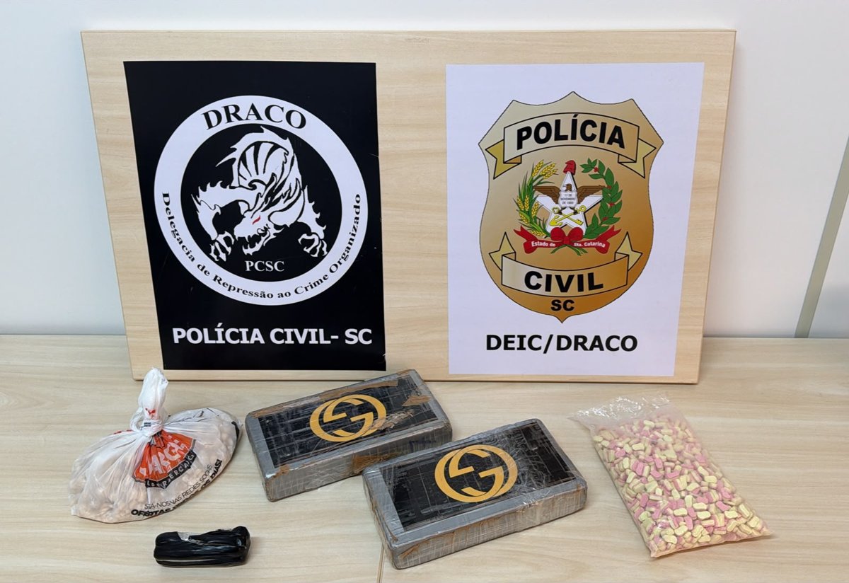 Drogas apreendidas expostas diante dos brasões da DRACO e da Polícia Civil de SC