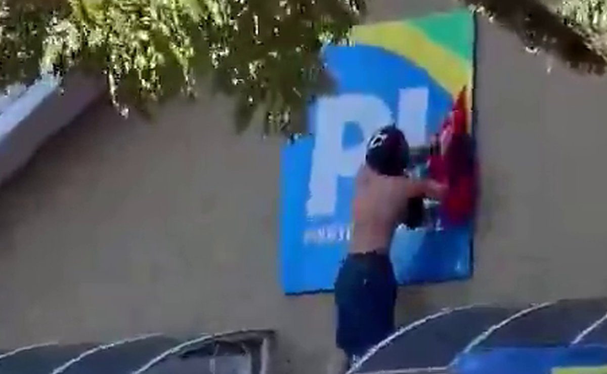 Encapuzados escalam a fachada da sede do PL e penduram bandeira durante ato pró-Lula em Curitiba