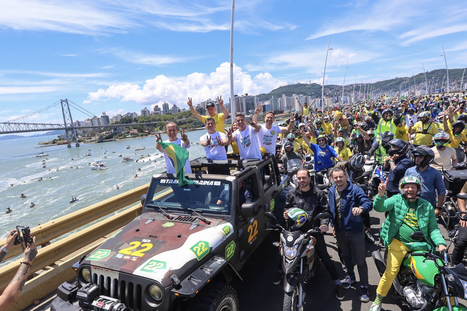 Jorginho Mello, Sergio Moro e Luciano Zucco no jipe da motociata, com jet skis na baía ao fundo