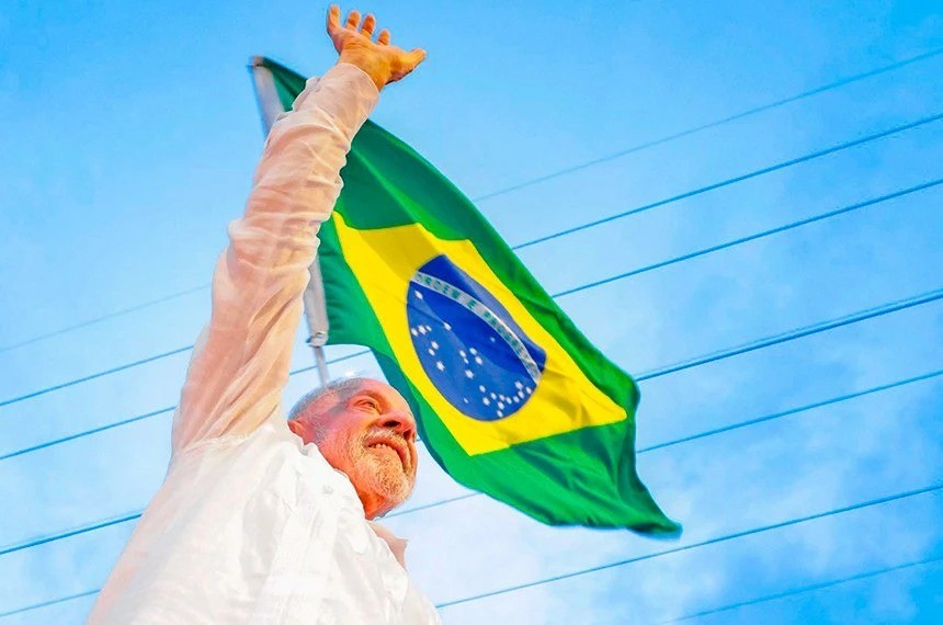 Lula com a bandeira do Brasil ao fundo