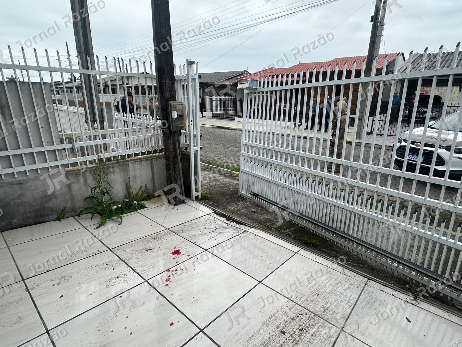Portão e marcas de sangue em frente a uma das casas da rua (Foto: Portal Agora)