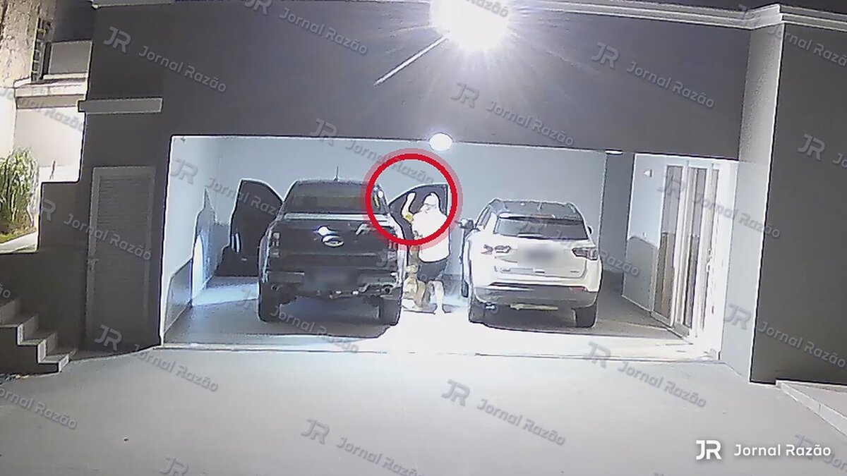 Imagem da garagem com círculo indicando a região em que o braço de Jaqueline se eleva junto a Fábio.